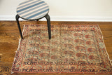 Upper right corner of antique Kerman rug, featuring weaver's signature cartouche and distressed paisley pattern.
