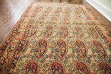 Lavar Kerman rug's allover paisley boteh pattern in beige, red, and blue, showing distressed wear.