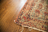 Worn edge and frayed threads of an antique Lavar Kerman rug, highlighting distressed Paisley design.