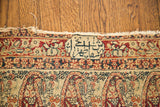 Weaver's signature cartouche on an antique Kerman rug, displaying red and cream Paisley motifs.