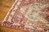 Antique Kerman rug with distressed red, blue, and ivory geometric motifs and worn fringe.
