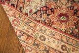 Distressed ruby red geometric pile and finely woven beige reverse of an antique Lavar Kerman rug.
