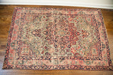 Antique Kerman rug's detailed central medallion with intricate floral designs and time-softened hues.
