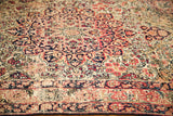 Antique Kerman rug showing blanched ivory field, muted red and dark blue curvilinear motifs.