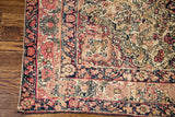 Worn, blanched floral border and soft coral, navy palette of this antique Kerman rug.