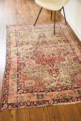 Worn fringe and blanched floral border on one end of the antique Persian Kerman rug.