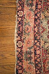 Antique Persian Kerman rug's worn edge, with blanched ivory and faded red floral patterns.
