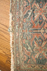 Vintage Lilihan rug's worn fringe and geometric pattern in muted blue, red, and green.