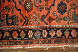Vintage Lilihan rug's dark border with muted floral motifs and frayed white fringe.