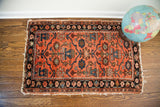 Bold vintage Persian Lilihan rug, worn reddish-orange field with dark blue floral design.