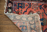 Worn red Lilihan rug detail showing intricate floral motifs and hand-knotted foundation.