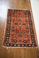 Early 20th century worn red Lilihan rug with bold floral pattern and dark botanical border.