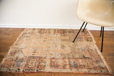 Worn tattered antique Turkish prayer rug displaying its blanched gold and beige neutral palette.