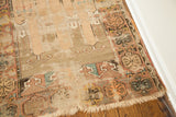 Frayed fringe and blanched, worn geometric patterns define a corner of this antique Turkish rug.