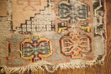 Worn edge, tattered fringe, and blanched geometric patterns on an antique Turkish prayer rug.