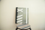 Minimalistic abstract painting on canvas with a bold geometric design in black, grey, and white.