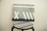 Modern abstract painting at an angle, showing its graphic white, grey, and black composition.