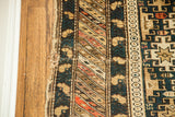Mended border of an antique Caucasian Shirvan rug, with dark blue, beige, and pinkish-orange geometric patterns.