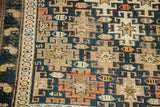Antique Caucasian Shirvan rug detail, featuring geometric patterns in deep blue, tan, and orange.