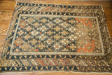 Aged lower corner of antique Shirvan Caucasian rug, geometric dark blue border, pinkish-orange field.