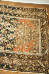 Antique Shirvan rug corner with geometric patterns in deep blue, coral, and natural tones.