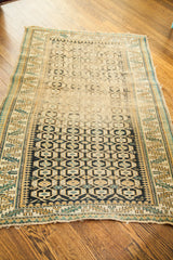 Hard wear on one end of a late 19th century Caucasian rug, with geometric charcoal and gold patterns.