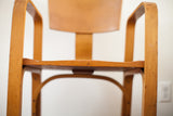 Bent plywood seat and armrests showing natural wood patina and surface markings.