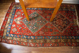Antique Heriz rug fragment's lower border, displaying intricate geometric patterns in red and teal.