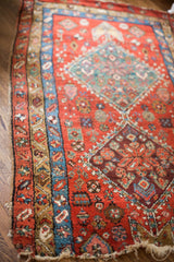 Antique Persian Heriz rug fragment with traditional geometric patterns in vivid reds, blues, and plum.