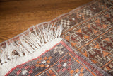 Folded Afghani rug showing white fringe, red edge, and dark geometric patterns.