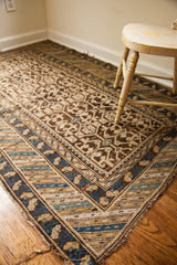 Fringed corner of an antique Caucasian rug, displaying intricate geometric patterns in blue and earth tones.