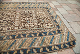 Antique Caucasian tribal rug corner featuring geometric patterns in brown, blue, and beige.