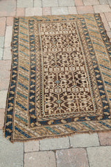 Antique Caucasian rug corner with tribal geometric blue, brown, and tan borders.