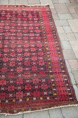 Afghani runner's geometric dark charcoal field and natural cranberry red border design.
