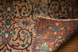 Tattered edge of vintage Tabriz rug, showcasing scrolling pattern and woven foundation.