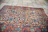 Vintage Tabriz rug's blue scrolling pattern on light gold, with tattered terracotta border.