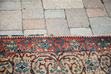 Vintage Tabriz rug's tattered edge with orange border and blue floral scrolling motifs.