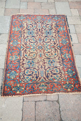 Vintage Tabriz rug corner: terracotta border, dark blue motifs, light gold field, tattered fringe.