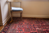 Blue willow tree motifs and storied wear on the raspberry red vintage Lilihan rug.