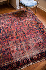 Vintage Lilihan rug corner, raspberry field, navy willow trees, traditional border, and wear.