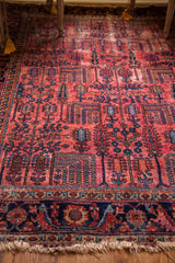 Vintage Lilihan rug's raspberry red field with willow trees, dark blue border, and fringe.