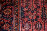 Vintage Lilihan rug's raspberry red field, navy blue stylized willow trees, isolated wear.