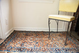Deep gold field with ornate blue botanical motifs on an antique Persian Yezd rug.