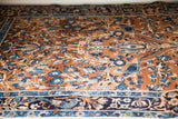Intricate blue and cream floral motifs on the antique Yezd rug's deep gold field.