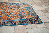 Detailed corner of an antique Persian Yezd rug, deep gold field, blue curvilinear border.