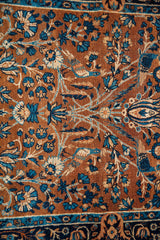 Deep gold field with intricate blue floral motifs and stylized bird designs on an antique Yezd rug.