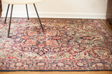 Section of antique Persian Kerman rug with curvilinear floral design in rich red, navy, and cream tones.