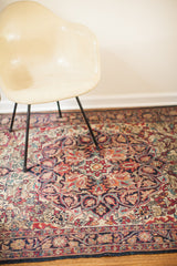 Decorative ruby red and navy curvilinear floral patterns on an antique Kerman rug.