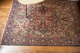 Ornate floral border detail with ruby, navy, and cream curvilinear vines on antique Kerman rug.