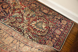 Antique Persian Kerman rug corner showing ornate floral pattern and tightly hand-knotted foundation.